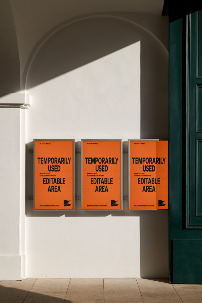 Three framed orange posters on beige wall beneath curved arch with green door nearby