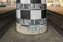 Striped pole wrapped with repeated black text in urban plaza street view