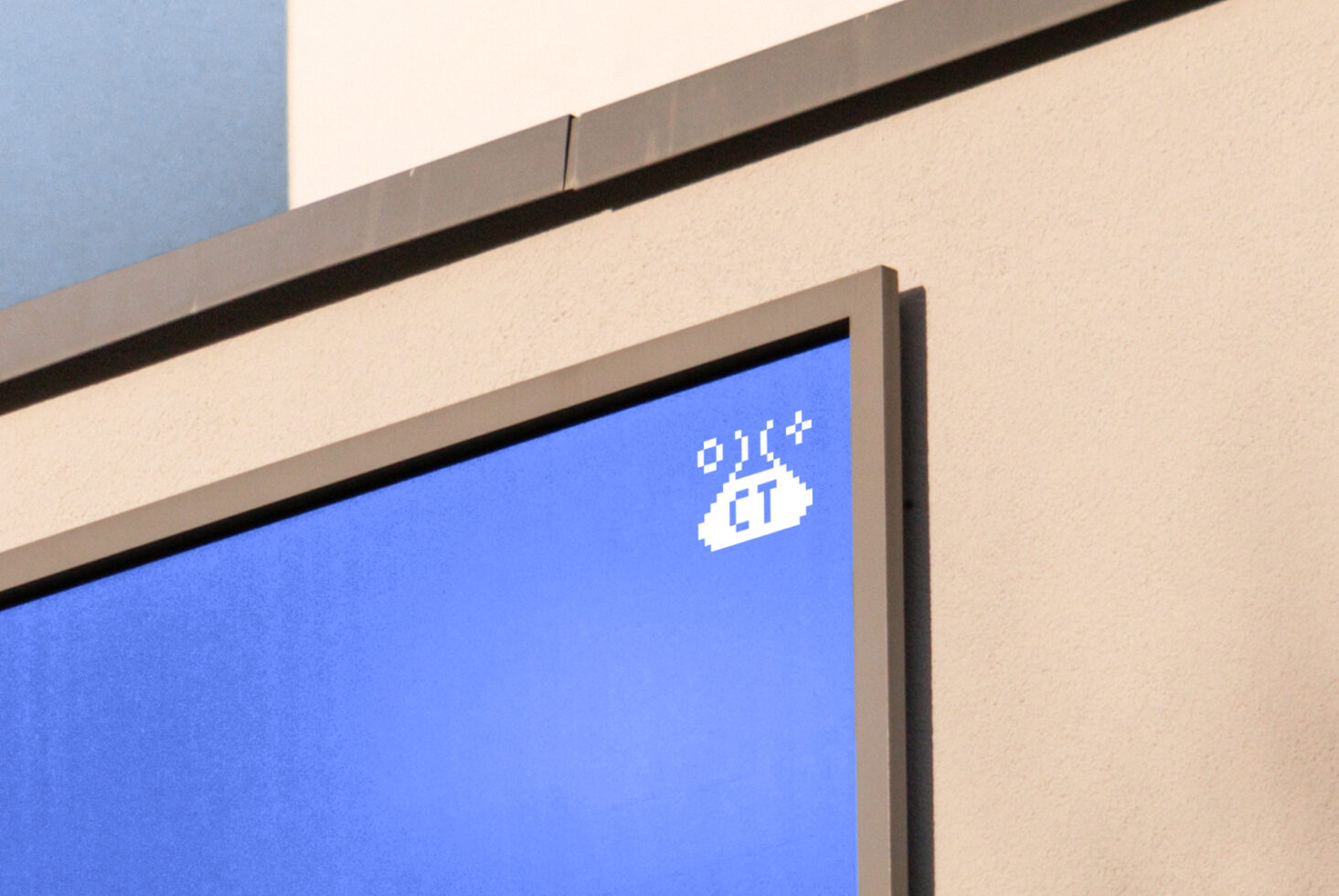 Blue display screen mounted on beige building facade showing white pixelated logo