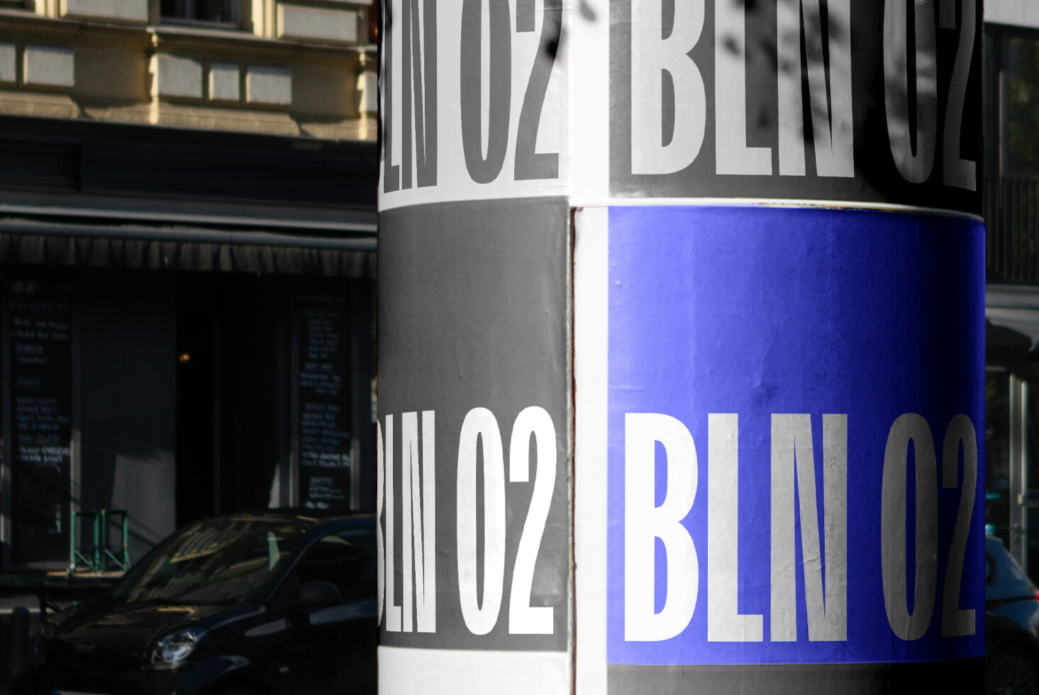 Close up of cylindrical storefront column wrapped with BLIN02 branding in blue, white, gray
