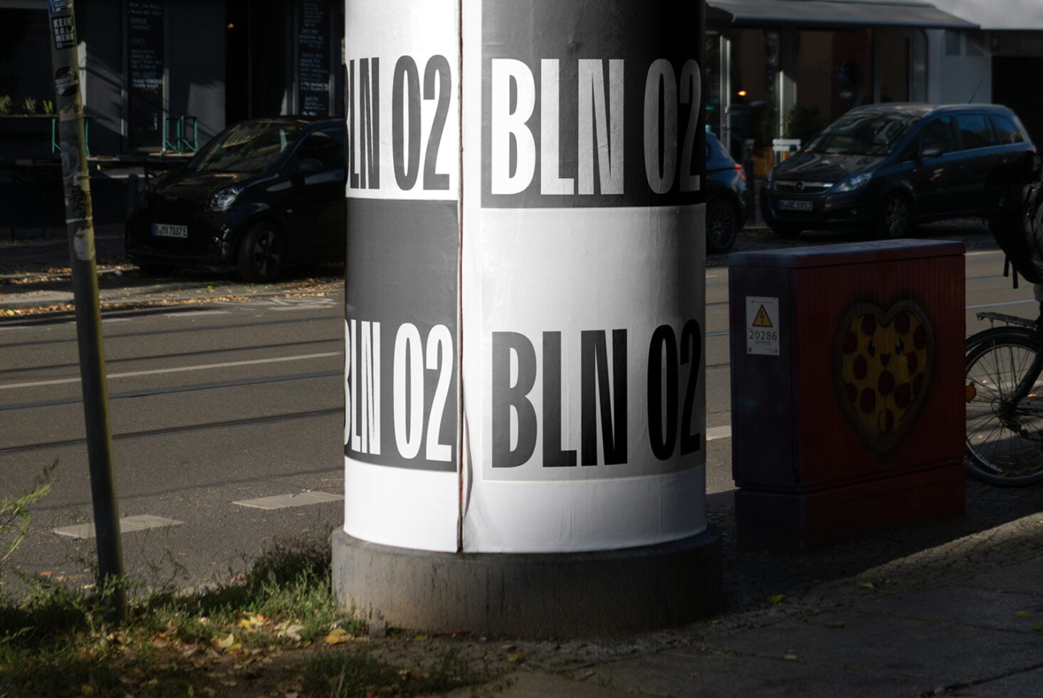 Street bollard wrapped in black white bands with bold Berlin typography during daytime