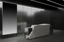 Neutral monochrome space, blank lit panel, white stone sculptural element, clean lines