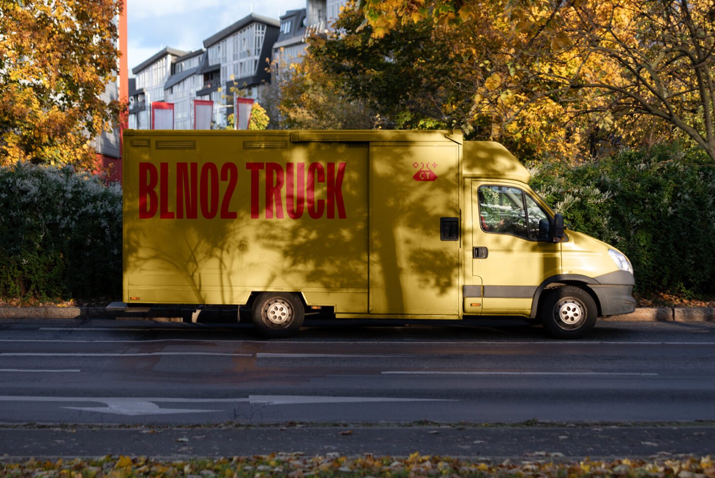 Yellow delivery truck parked on urban street with trees in autumn. Perfect for graphic design mockup. Ideal for branding or advertising template use.