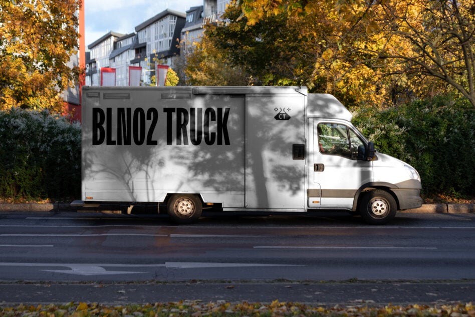 White delivery truck with bold black text on cargo box, autumn trees behind