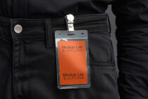 ID badge clipped to black denim with solid orange card design