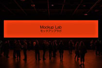 Bright orange display panels with Mockup Lab text, crowd viewing below