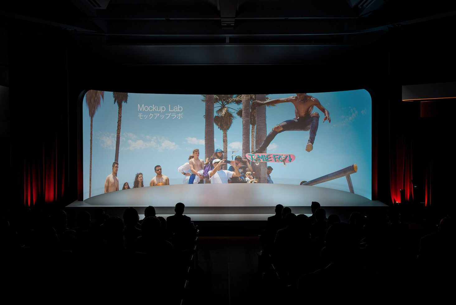 Large cinema screen displaying beach scene with people and skateboarder viewed by an audience, ideal for presentation and event mockup templates.