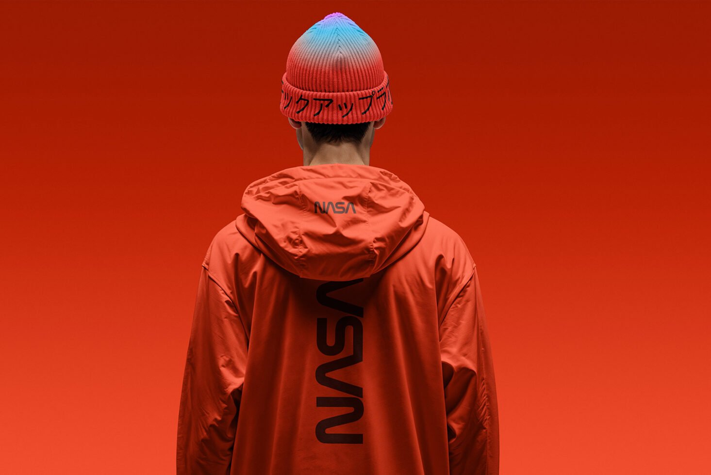 Back view of person in orange jacket with NASA logo wearing red-blue gradient beanie on orange background. Suitable for fashion mockups and design assets.