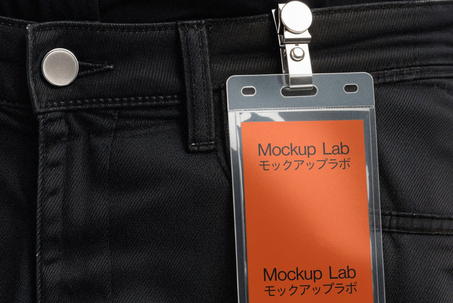 Close-up of a black denim jeans pocket with an orange mockup identity badge clipped on. Ideal for branding presentations, mockup designs, templates.