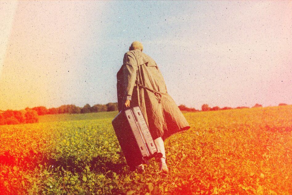 Person walking away across blooming field with suitcase under dreamy warm color-graded sky