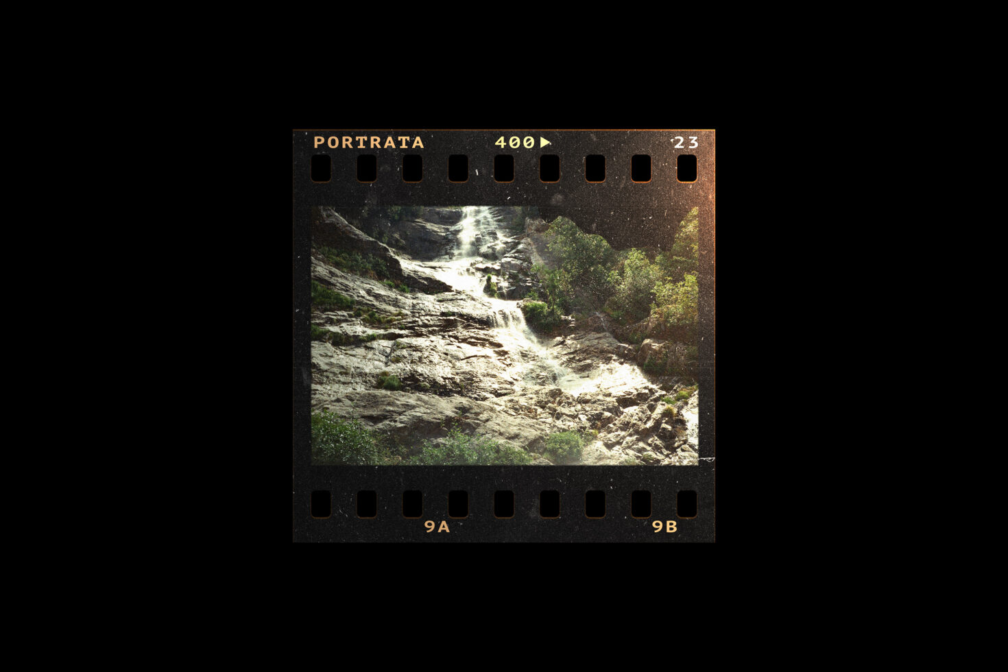 Vintage film photograph of a waterfall cascading over rocky terrain surrounded by greenery. Perfect for designers looking for nature and retro-themed graphics.