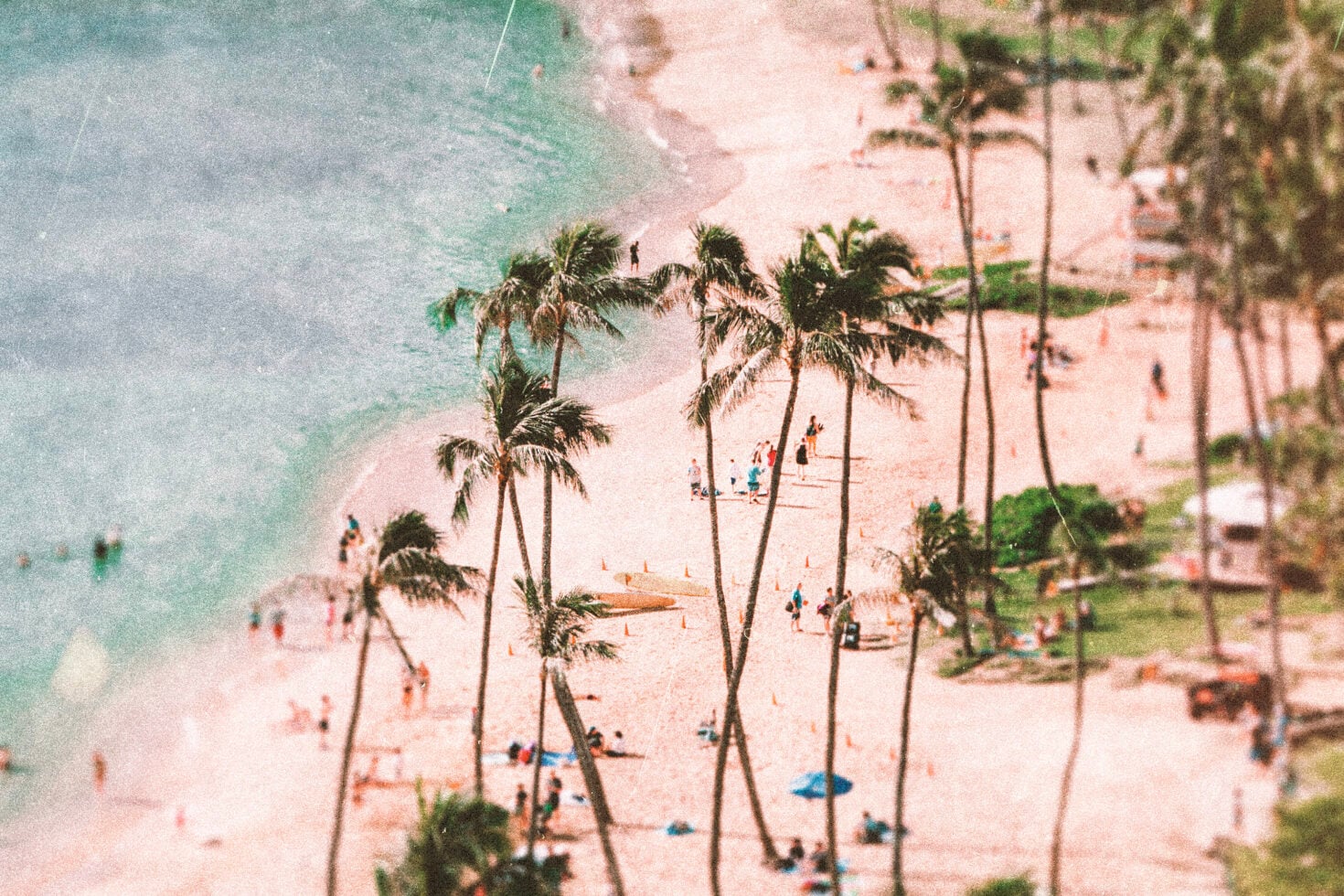 Pastel aerial beach scene, turquoise water, palm trees, scattered figures, soft grain texture