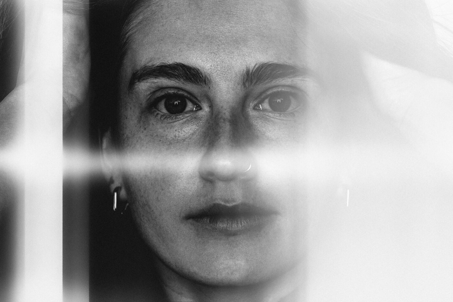 Black and white close-up portrait of a person with a serene expression and soft light effect creating an ethereal, artistic atmosphere for creative projects.