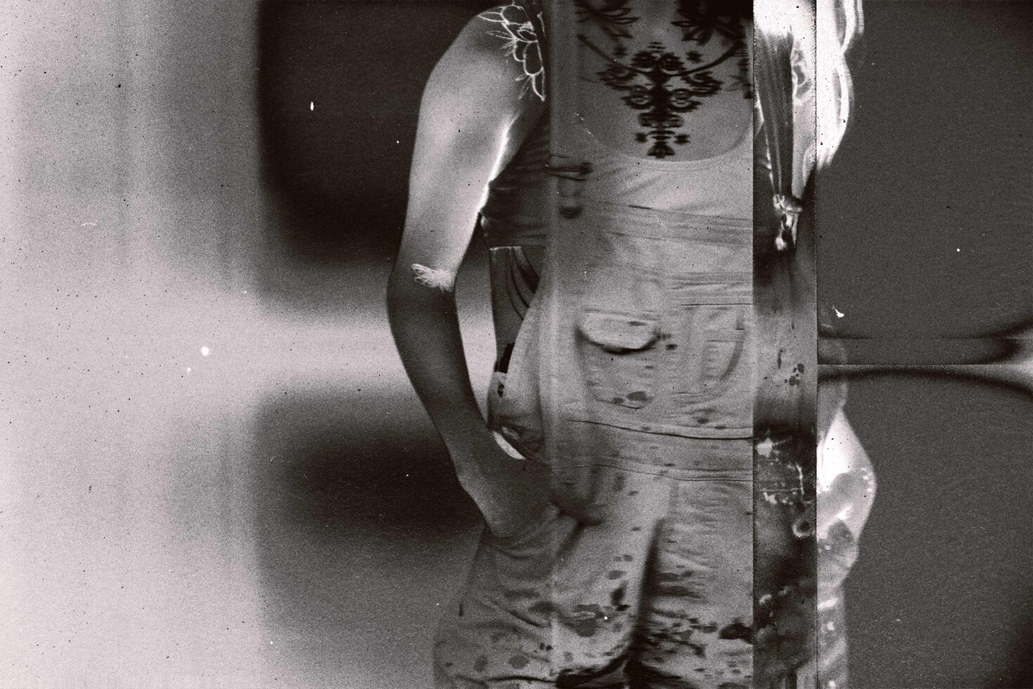 Vintage black-white film frame detail of person in embroidered costume, grain texture