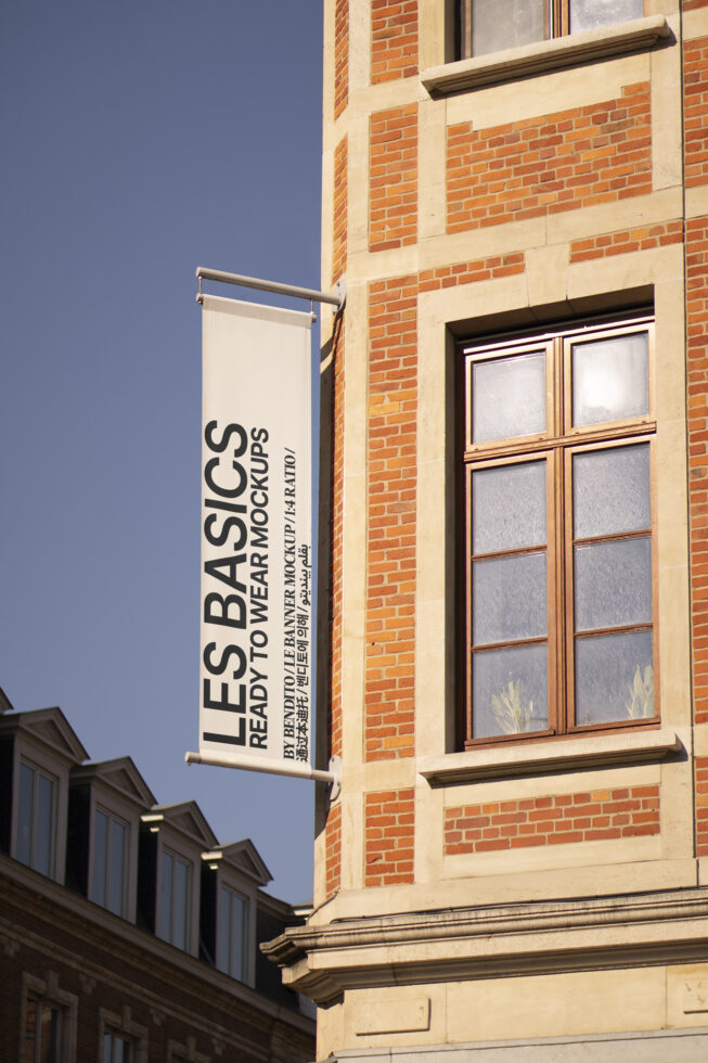 Building facade with vertical banner mockup displaying Les Basics in urban setting. Perfect for showcasing outdoor advertising designs.