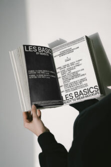 Magazine mockup with cream left page, dark right page, held open displaying Les Basics content