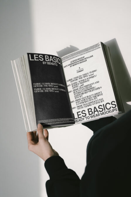 Magazine mockup with cream left page, dark right page, held open displaying Les Basics content