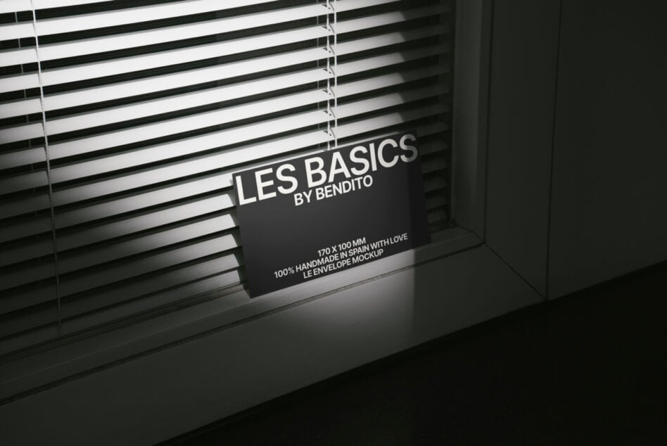 Black business card mockup on surface beneath horizontal window blinds