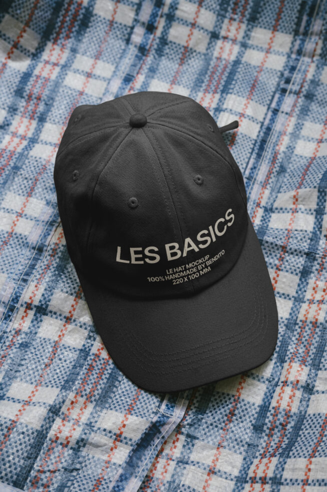 Black baseball cap with Les Basics embroidered text on checkered fabric background