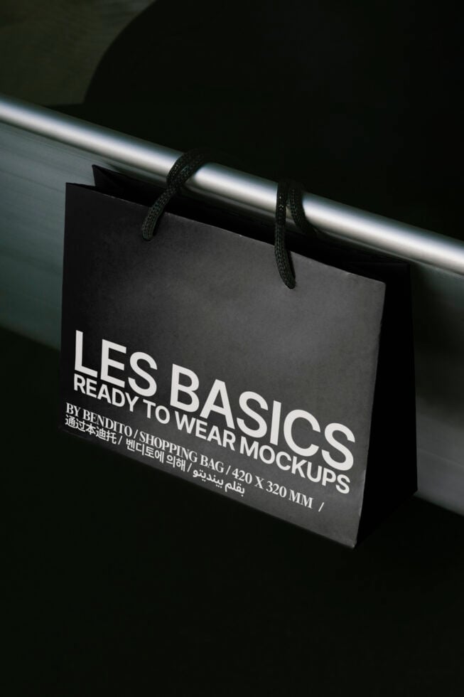 Shopping bag mockup hanging on a metal rail displaying Les Basics design ready for wear. Perfect for mockup presentations graphics templates designers.