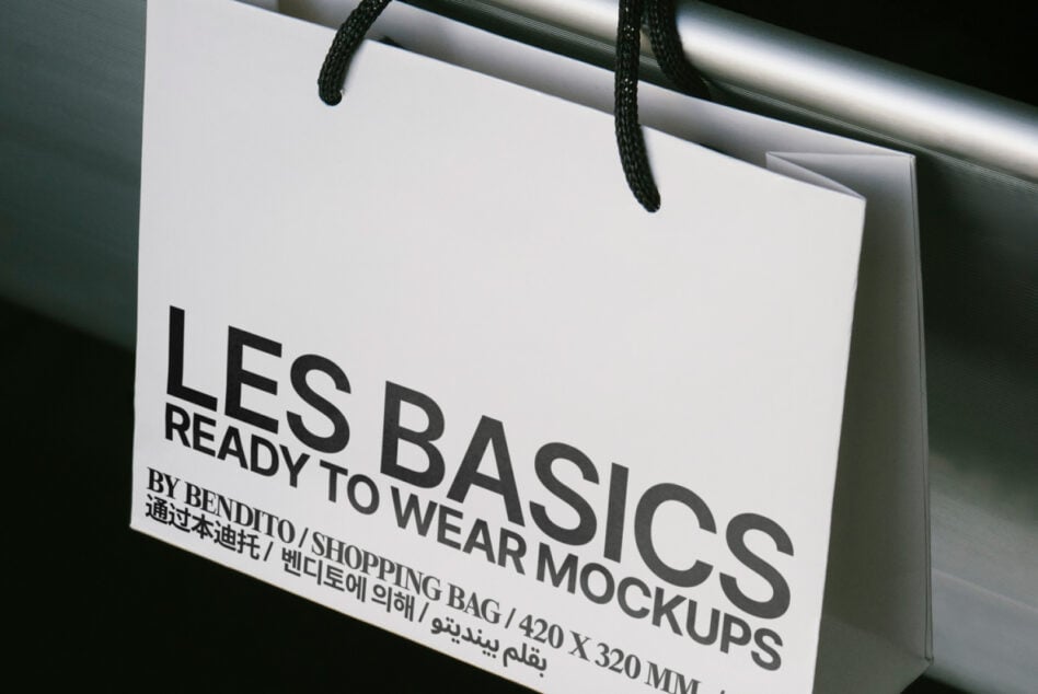 Shopping bag mockup with Les Basics text for design assets marketplace. Features black print on white paper. Ideal for fashion branding templates.