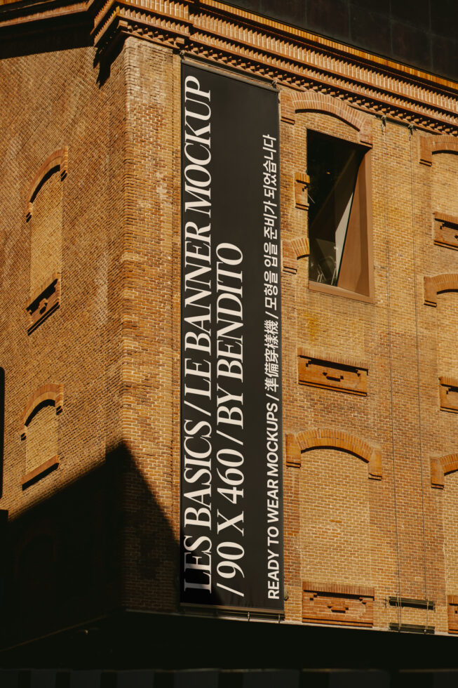 Red brick industrial building with dark banner mockup showing typography, ornamental cornice details