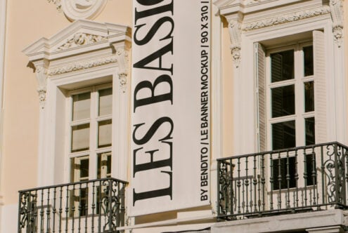 Vertical banner mockup displayed on an elegant building facade showcasing classic architectural details. Perfect for designers seeking realistic graphics.