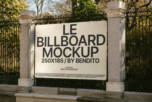 Billboard mockup template displayed outdoors on a stone and metal fence. Perfect for designers showcasing ads, posters, and promotional graphics.