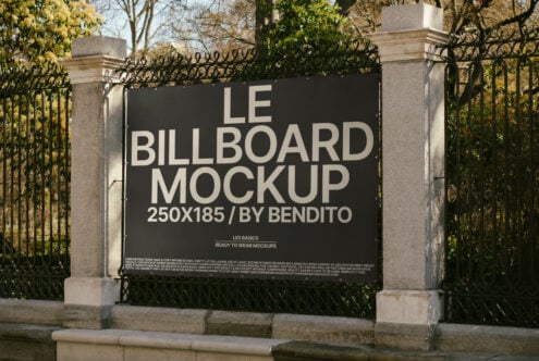 Billboard mockup in urban park setting with classic iron fence in background ideal for designers needing realistic outdoor advertising presentation templates.