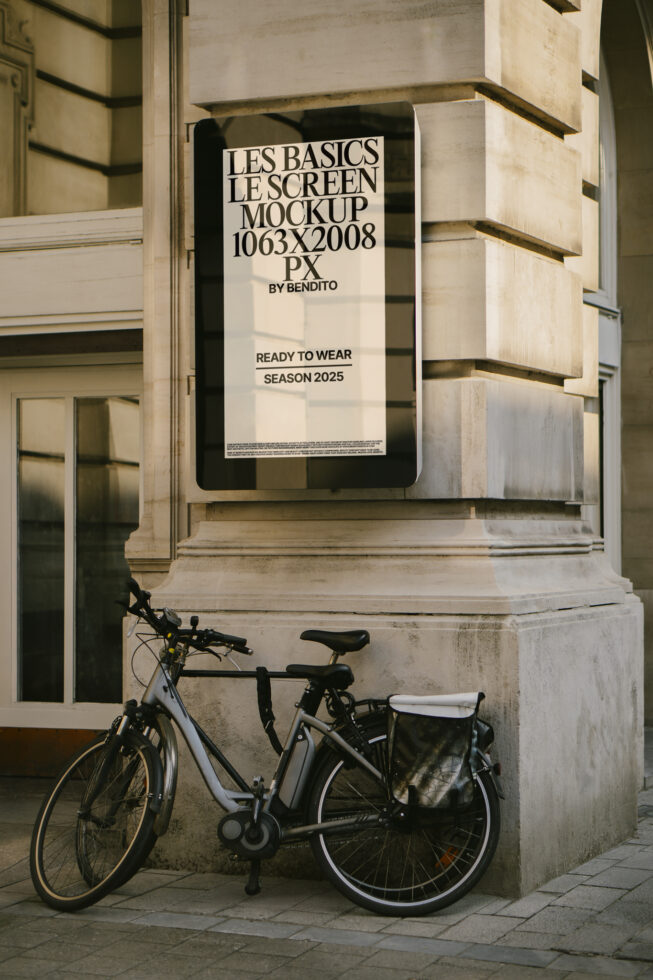 Outdoor screen mockup on stone building featuring bike parked nearby. Ideal for urban advertising templates. Keywords: mockup design template SEO.