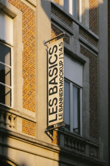 Street hanging banner mockup on urban building facade with cream background