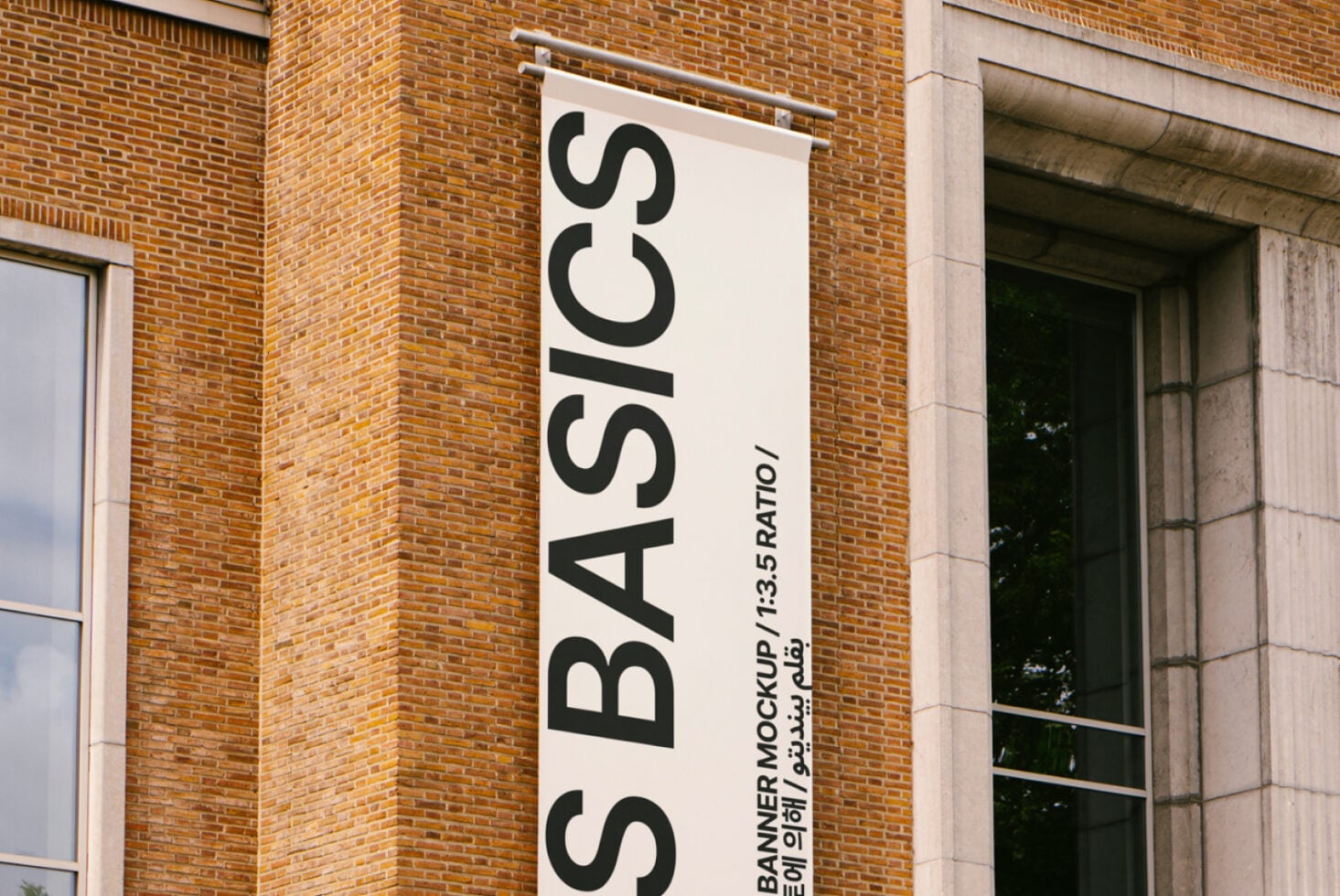 White vertical banner mockup on brick facade with black large text S BASICS