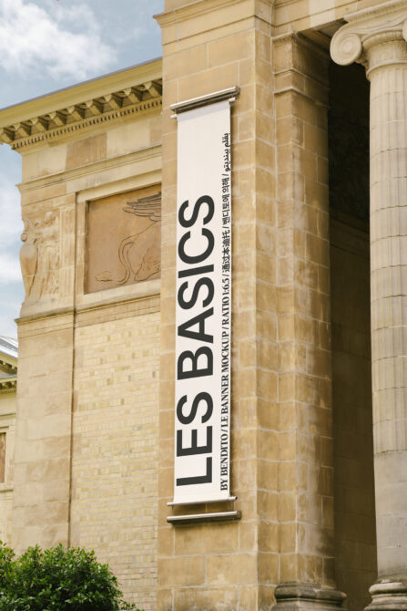 White vertical banner mockup on sandstone building with black text reading LES BASICS
