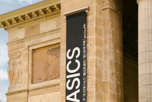 Vertical black banner on historical building with large white text and multilingual script. Ideal for architecture mockup or typography design template.