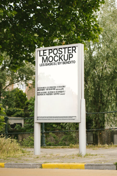 White poster mockup on tall stand with leafy trees partially framing the scene
