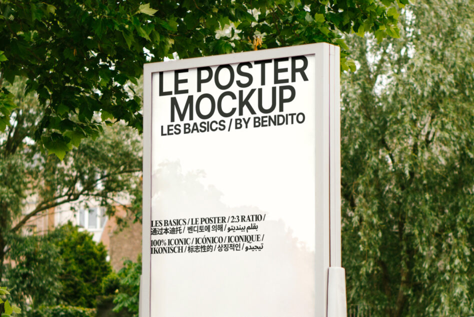 White poster mockup on vertical pole beneath hanging green tree foliage