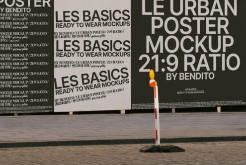 Urban poster mockup display with LES BASICS branding in 21:9 ratio. Perfect for designers seeking realistic street graphics. Outdoor scenery included.