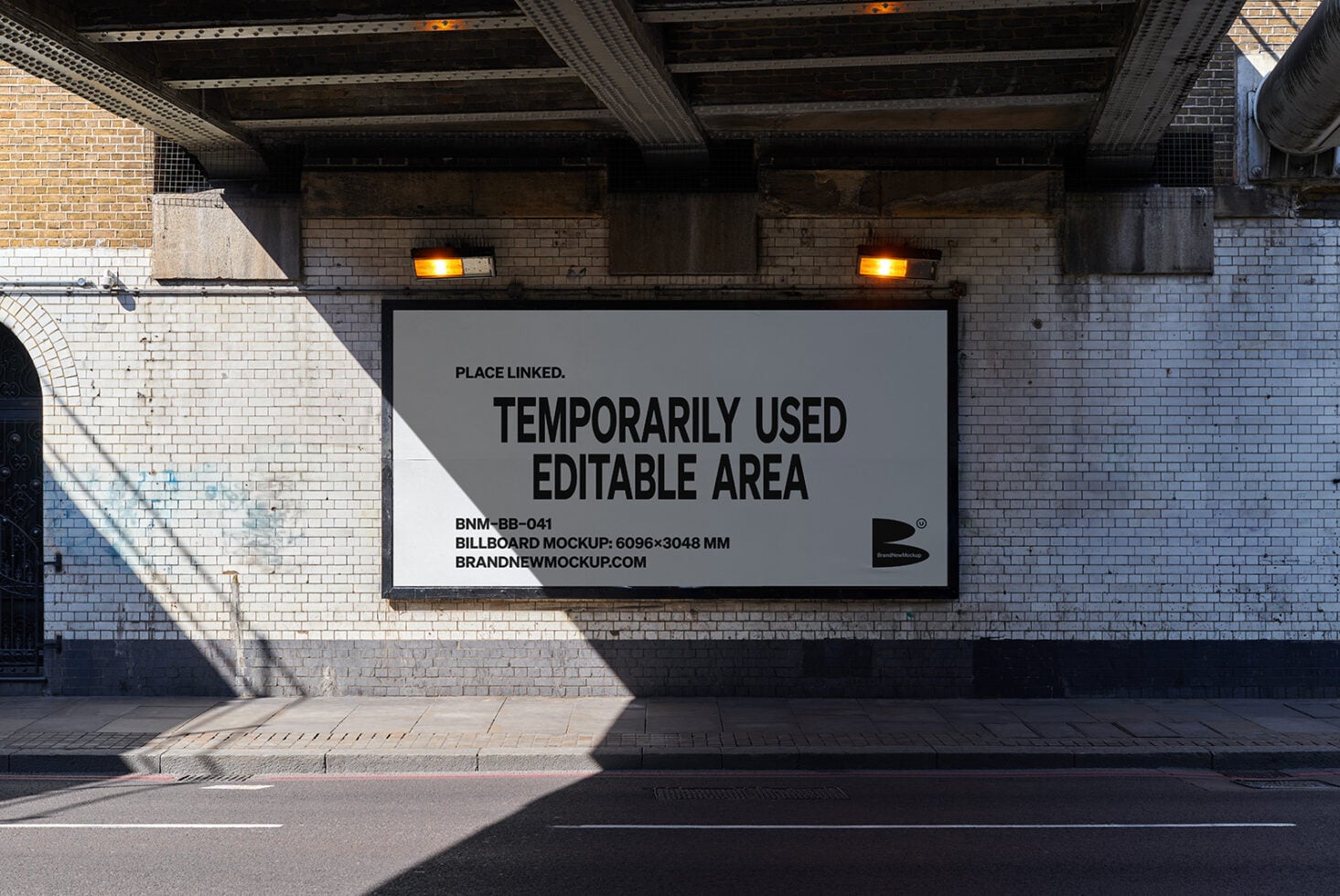 Large horizontal billboard mockup on brick underpass with amber lights overhead