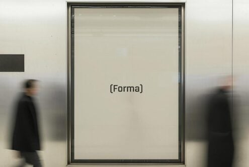 Blurred motion of two people walking past a large window with the word Forma in a modern font. Ideal for designers seeking typographic inspiration.