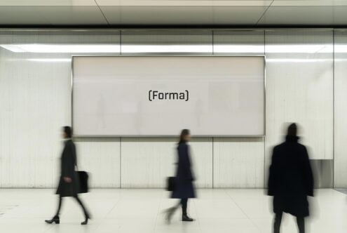 Large wall-mounted digital display mockup in modern interior setting with blurred figures walking by. Perfect for showcasing branding or advertising designs.