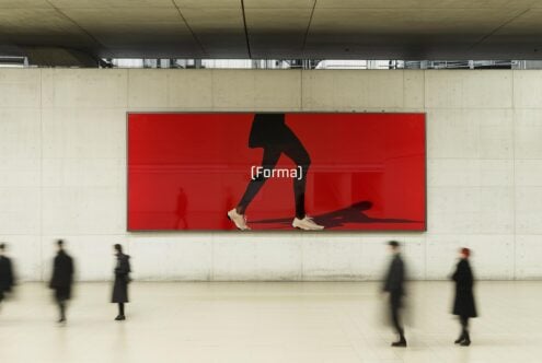 Large advertising mockup featuring a person walking on a red background in a modern hallway setting ideal for design presentations and branding displays.