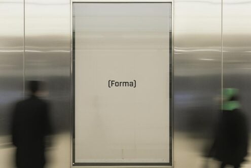 Large framed Forma poster in modern hallway with blurred people passing by. Ideal for mockup use. Keywords: modern, mockup, poster, design asset.