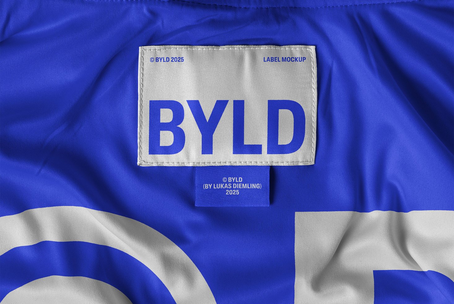 Close-up of a blue fabric label mockup displaying the text BYLD in bold. Ideal for product packaging design, textile mockups, and branding projects.