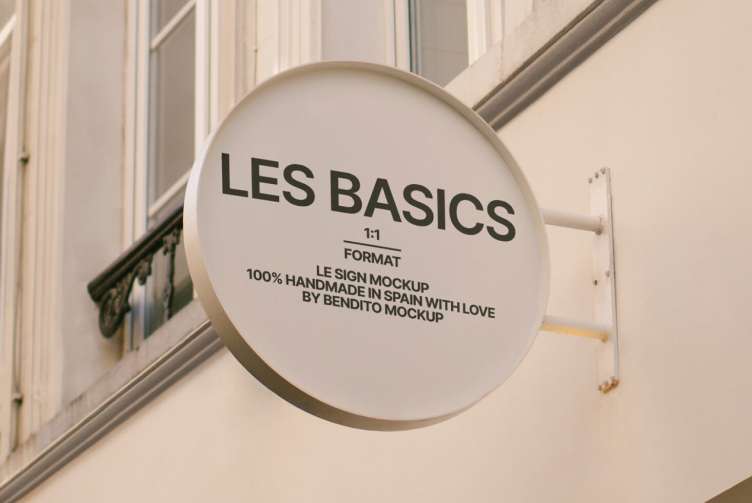 Round sign mockup displaying text LES BASICS mounted on building exterior. Ideal for branding design presentations. Mockups graphic design templates.