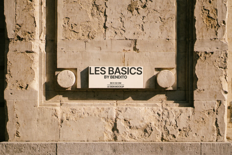 Cream-colored horizontal sign with black text mounted on textured stone wall with circular architectural details