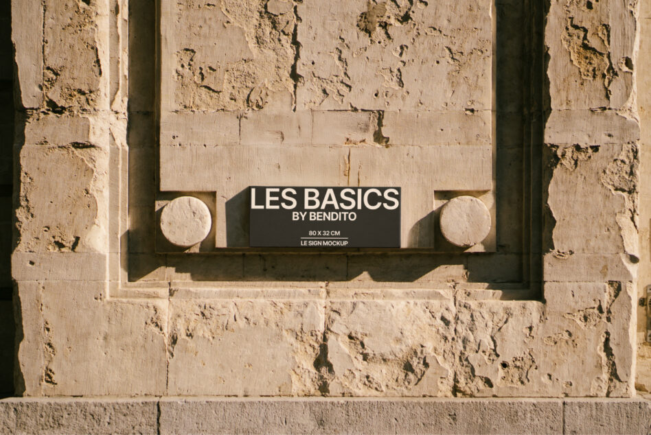 Black horizontal sign with white text mounted on textured stone wall with circular architectural details