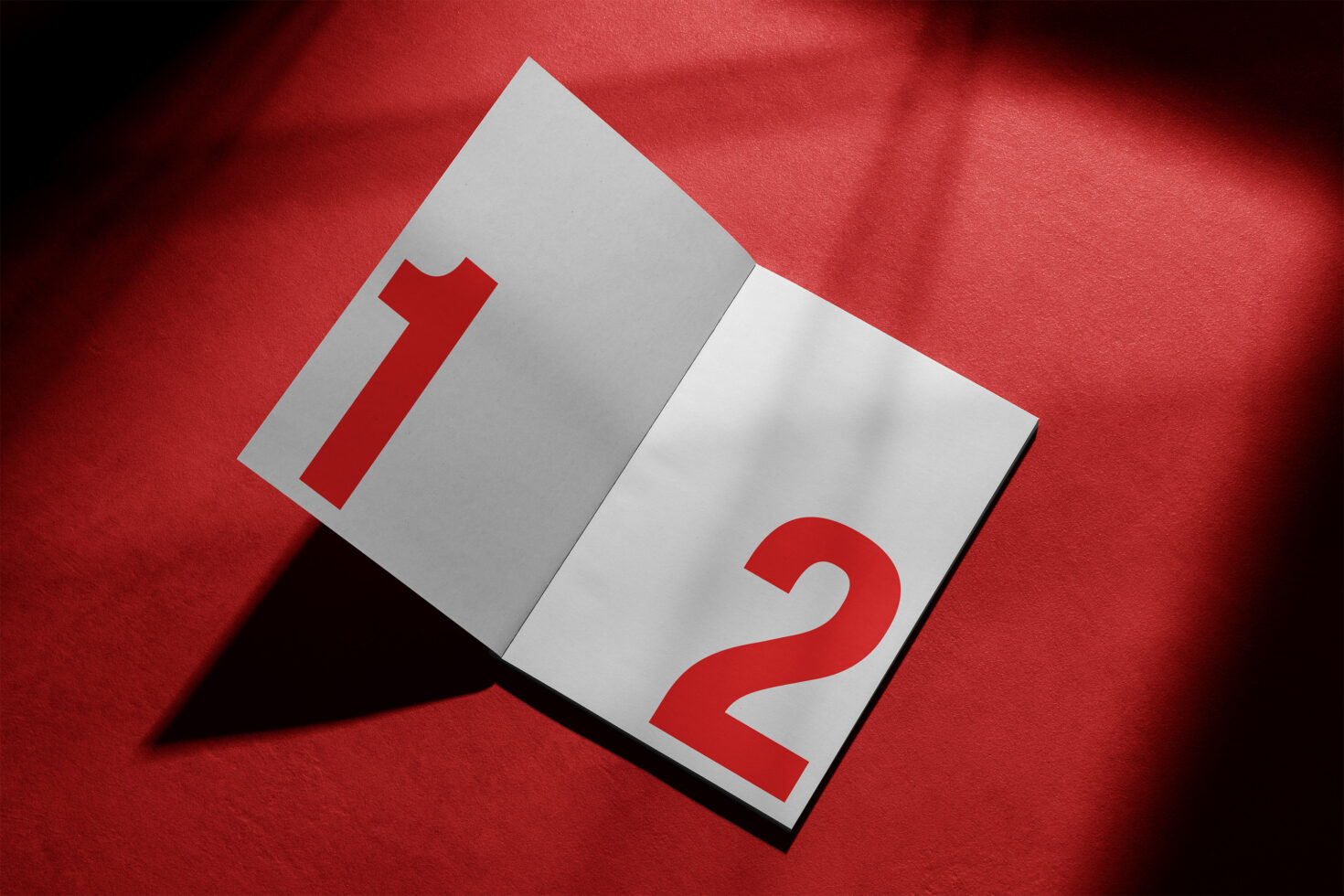 Open booklet mockup on red background with large red numbers 1 and 2. Perfect for graphic design, templates, and layout presentations. Professional asset.