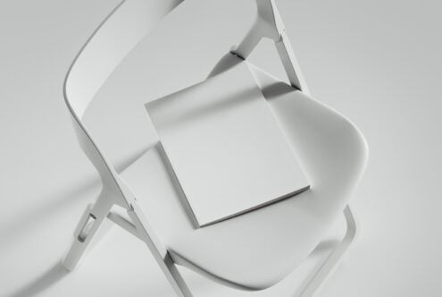 Minimalist mockup of a white blank magazine on a modern chair ideal for showcasing design layouts templates branding and print presentations for designers.