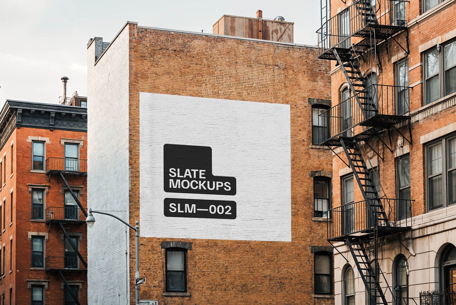 Urban brick wall with mockup design featuring Slate Mockups logo. Ideal for showcasing marketing materials in architectural settings. Exterior wall template.