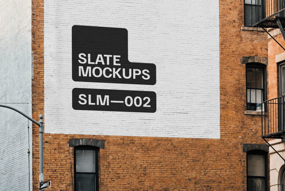 Black stencil signs on white painted brick wall between red buildings